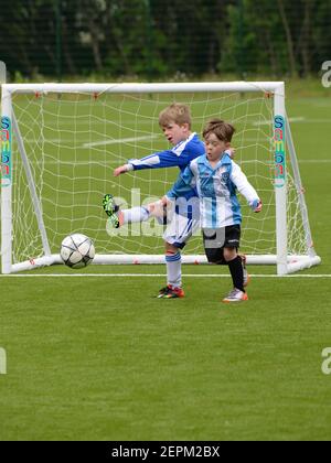 Two small boys play 7 a side organised football on an artificial surface in Glasgow, Scotland, UK, Europe Stock Photo