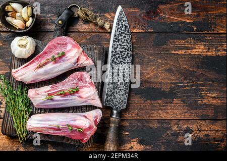 Raw veal shanks meat on a cutting board with herbs. Dark wooden background. Top view. Copy space Stock Photo