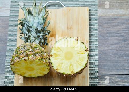 A pineapple sliced into half on wooden board Stock Photo