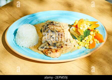 Fried fish with rice and vegetables on blue plate Stock Photo