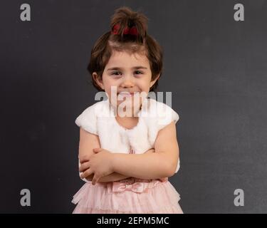Young girl standing with arms crossed isolated against a chalkboard. Mood feelings personality and facial expression concept. Stock Photo
