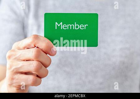 A young caucasian woman is holding a green card that says member on it. A customizable image which has space for text to be inserted. Being a member, Stock Photo