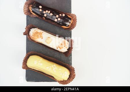 Three eclairs on a black tray top view Stock Photo