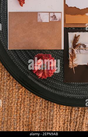 Top view of white greeting cards placed on black round tray with bright plants on wicker surface during wedding celebration Stock Photo