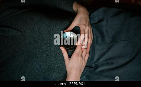 Close up view of anonymous relaxed female lying on carpet holding transparent crystal ball with hands Stock Photo