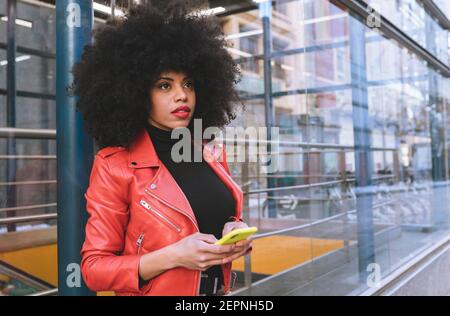 Fill body side view of confident African American female with Afro hairstyle standing on sidewalk and looking away Stock Photo