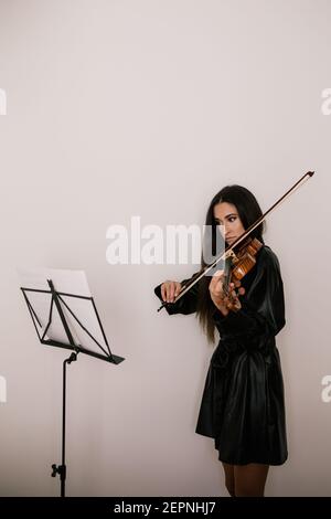 Side view of female owner with cute white French Bulldog standing in light room at home Stock Photo