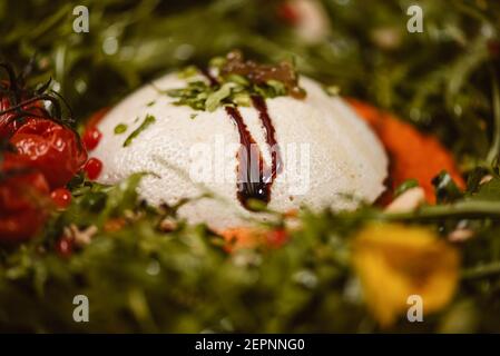 Close up view of yummy burrata cheese on cold tomato cream with arugula leaves and cherry tomatoes with truffles and peanuts Stock Photo