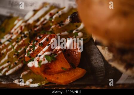 Close up of yummy burger with vegetarian patty and grilled shiitakes between buns near sweet potato and carrot slices with alioli sauce on dark backgr Stock Photo