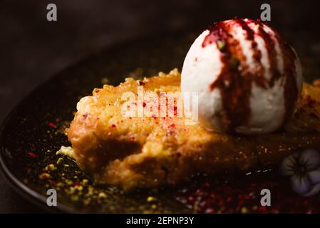 Close up of yummy French toast with meringue milk ice cream scoop covered with sweet berry sauce on plate with condiments in restaurant on dark backgr Stock Photo