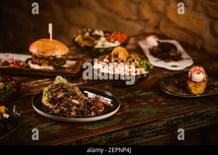 Appetizing vegetarian dishes with sauteed mushrooms and vegetables near burger and ice cream with French toast on wooden table Stock Photo