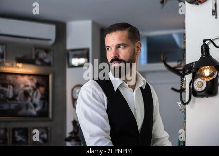 Adult brutal male executive in formal wear looking away in hairdressing salon Stock Photo