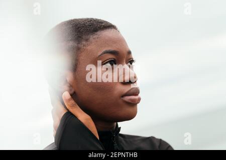 Young contemplative ethnic female with short hair touching face in daylight Stock Photo
