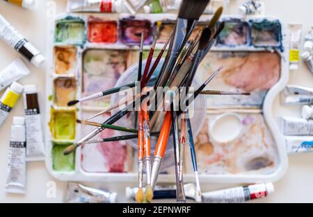 High angle multicolored paintbrushes of different sizes placed on watercolor palette Stock Photo