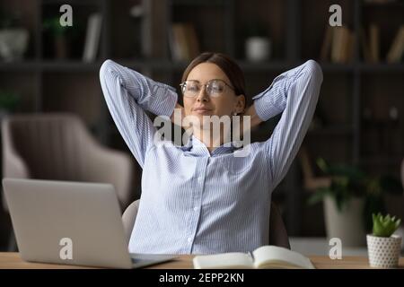 Calm young Caucasian woman relax at desk in office Stock Photo
