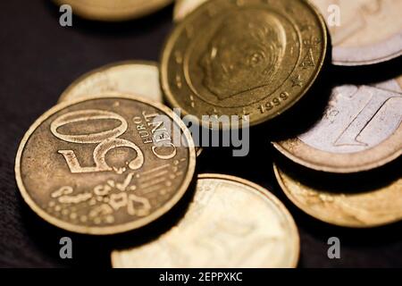 Shallow depth of field (selective focus) and macro image with a 50 Euro cents metal coin near other Euro coins on black background. Stock Photo