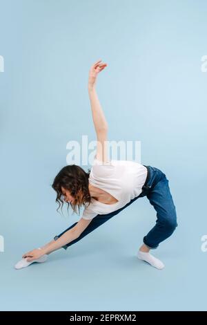 Hard working contemporary dancer poses in front of blue studio background.  Her legs in a lunge, body twisted. She's arched, looking back. Stock Photo  | Adobe Stock