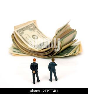 Two businessmen observing a large pile of cash against a plain background in focus on financial success and wealth creation Stock Photo