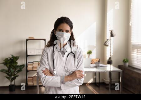 Portrait professional female doctor wearing medical mask standing in office Stock Photo
