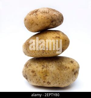 Stacked potatoes showcasing various shapes and sizes under natural light in a simple setting Stock Photo