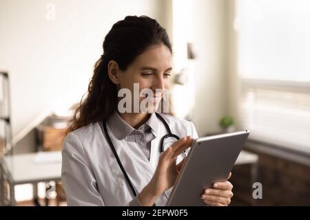 Close up smiling female doctor using tablet, standing in office Stock Photo