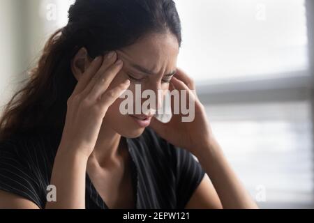 Close up unhappy woman touching temples, suffering from strong headache Stock Photo