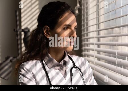 Head shot close up female doctor dreaming, looking out window Stock Photo