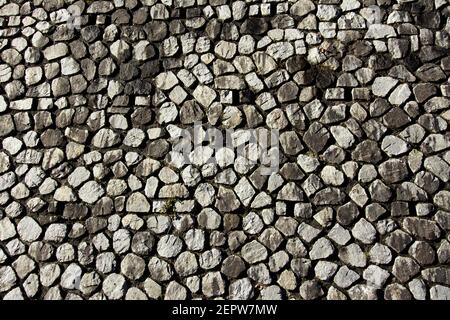 Textured stone wall pattern featuring various shapes and sizes of stones in a natural arrangement highlighting different hues Stock Photo