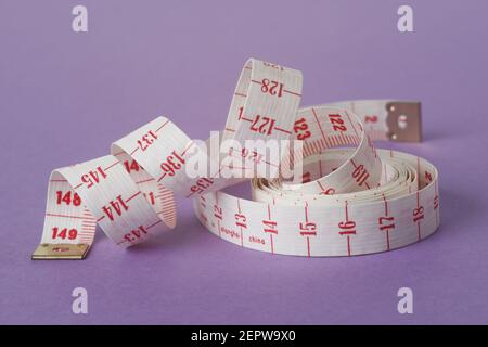 Measuring tape isolated on purple background and partially unwound into a spiral Stock Photo
