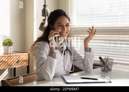 Smiling professional female doctor talking on phone, consulting patient Stock Photo
