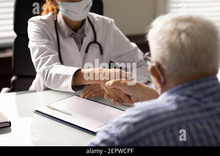 Close up back view doctor and senior patient shaking hands Stock Photo