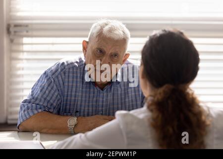 Close up serious old man listening to doctor at meeting Stock Photo