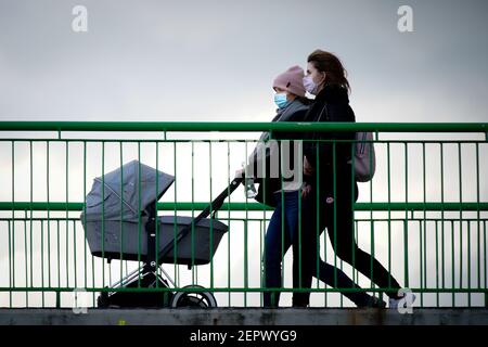 (210228) -- WARSAW, Feb. 28, 2021 (Xinhua) -- Two women wearing face masks are seen with a stroller crossing a bridge in Warsaw, Poland, on Feb. 27, 2021.  The Polish government announced new restrictions on Wednesday in an effort to curb a recent rise in new COVID-19 infections officially dubbed the 'third wave.'   Health Minister Adam Niedzielski said that the rules on face covering will be tightened, mandating the use of masks in public spaces starting on Saturday instead of the previously allowed alternatives, such as scarfs and visors.   Also starting on Saturday, travelers from southern Stock Photo