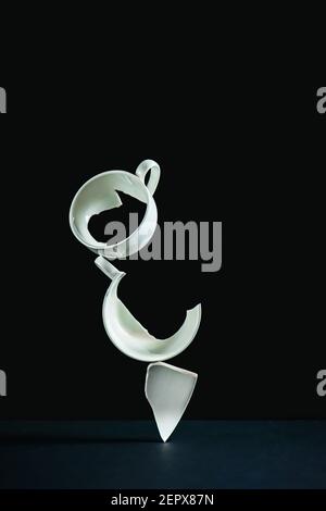 Broken cup balancing construction, porcelain shards on a black background Stock Photo