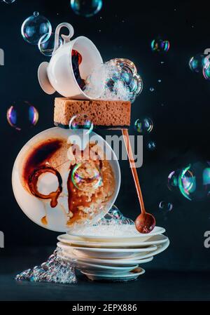 Dirty dishes and coffee cups with sponges and bubbles, mundane beauty concept Stock Photo