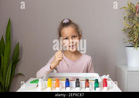 Cute little blond girl drawing with ebru paints at home Stock Photo