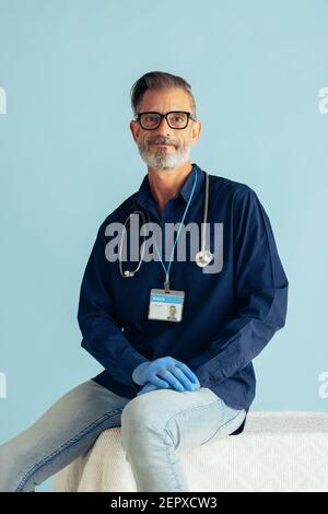 Portrait of a confident male doctor on blue background. General practitioner with stethoscope looking at camera. Stock Photo