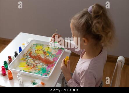 little girl drawing with ebru paints on water Stock Photo