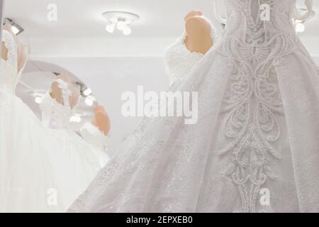 Wedding dresses on mannequins at shop. Interior of bridal salon. Defocused photo with soft focus. Stock Photo