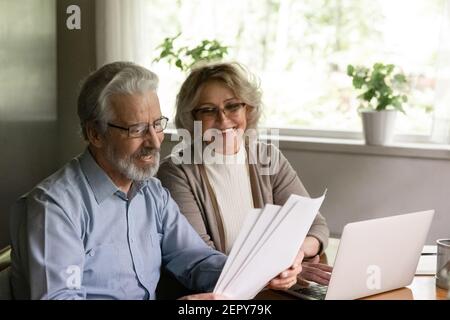 Happy older family couple reading and checking financial documents Stock Photo