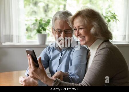 Happy mature couple using smartphone for video call from home Stock Photo