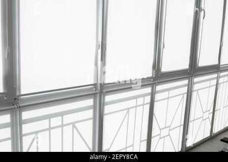 White fabric roller blinds on the plastic window on a balcony in the living room. Stock Photo