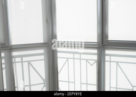 White fabric roller blinds on the plastic window on a balcony in the living room. Stock Photo