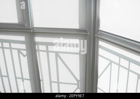 White fabric roller blinds on the plastic window on a balcony in the living room. Stock Photo