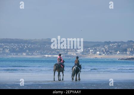 Marazion, Cornwall, UK. 28th February 2021. UK Weather. Horse riders on the beach at Marazion today, in the warm sunshine ahead of the start of spring on Monday. Credit Simon Maycock / Alamy Live News. Stock Photo