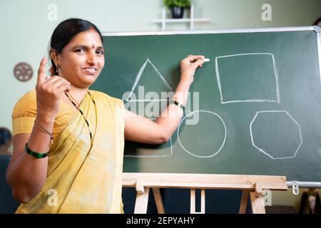 Indian woman busy explaining from board during online class by looking camera at home - Concept of e-teaching, Remote learning, virtual education Stock Photo