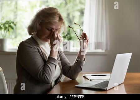 Mature 60s pensioner tired of using laptop at home Stock Photo