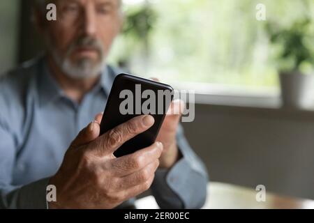 Older 70s aged man using online app on mobile phone Stock Photo
