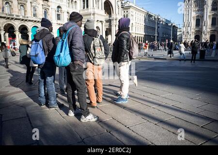Milan, Italy - January 11, 2019: African black males, men, immigrant standing on Milan Duomo square, with tourists Stock Photo