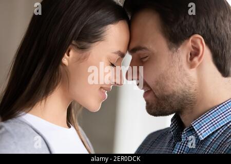 Happy millennial couple in love touching with foreheads